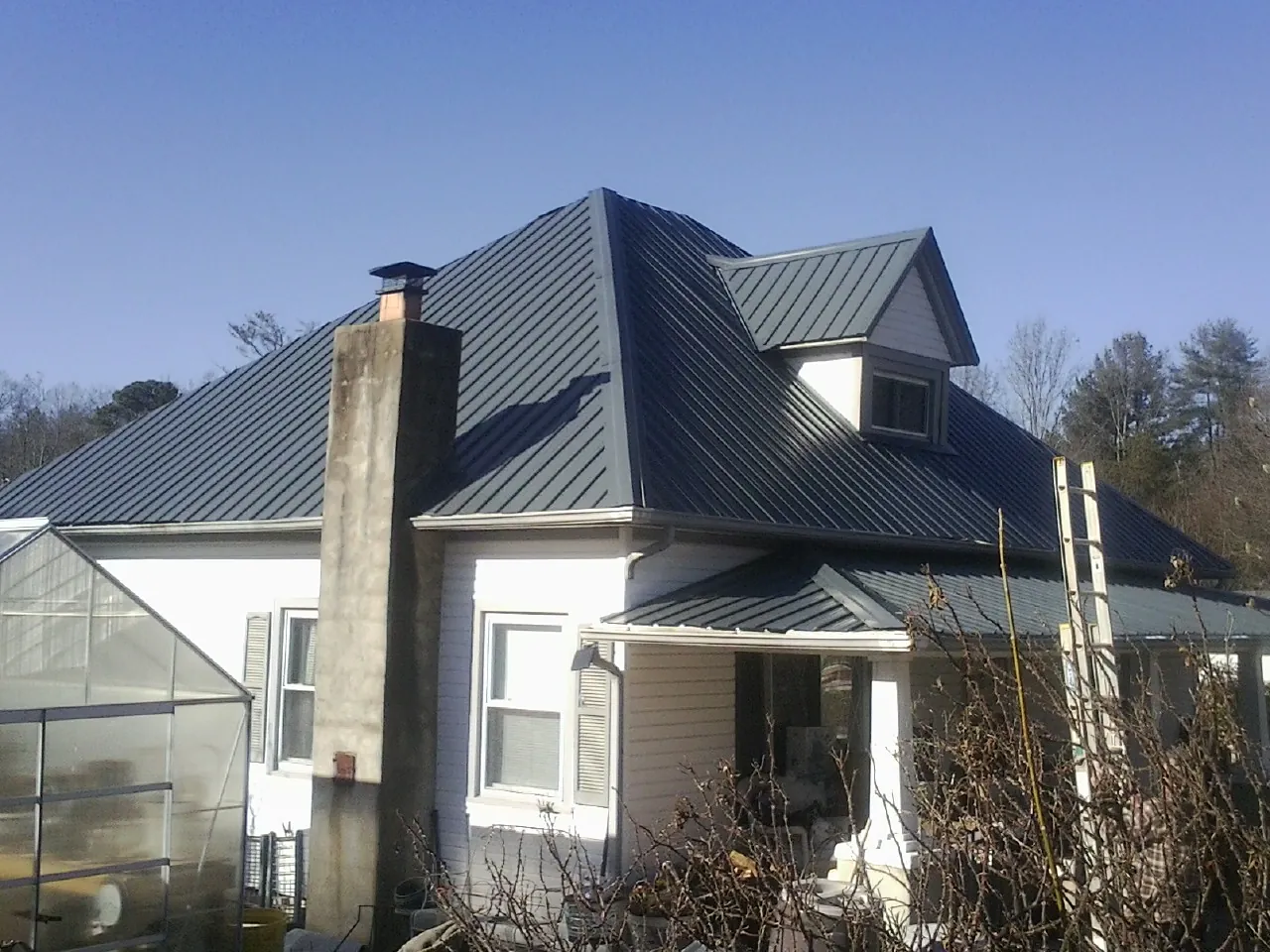 Dark blue standing seam metal roof on a white farmhouse with dormer — Slate & Tile Roof Repair by Roofing Brothers in Bonney Lake