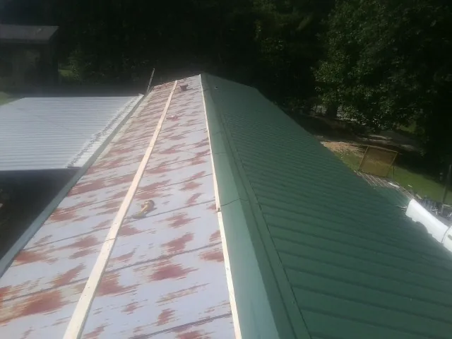 Old rusted panels beside newly installed green metal roofing — Wind Damage Roof Repair by Roofing Brothers in Bonney Lake