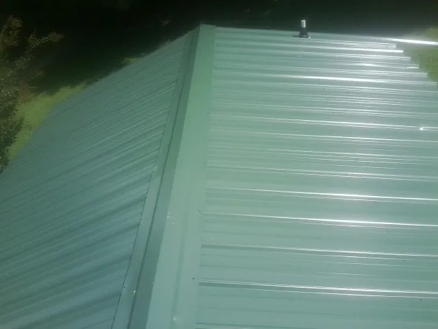 New green metal panels meeting at the ridge of a roof — Flat Roof Repair work by our crew in Bonney Lake