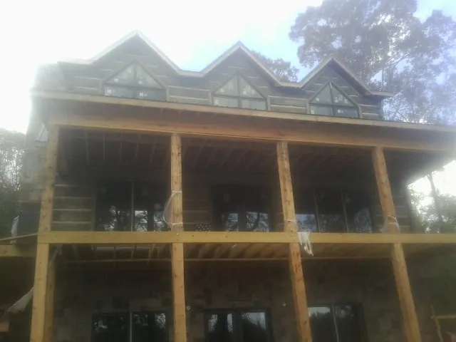 Dormers and porch framing on a large log home under construction — Roof Coating work by our crew in Bonney Lake
