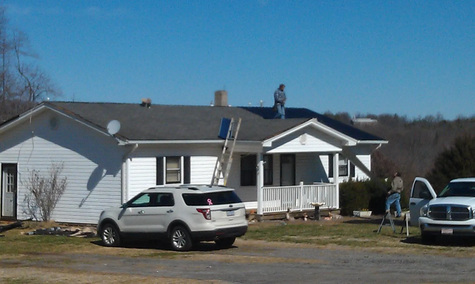 Roofers stripping shingles from a white ranch house roof in Bonney Lake