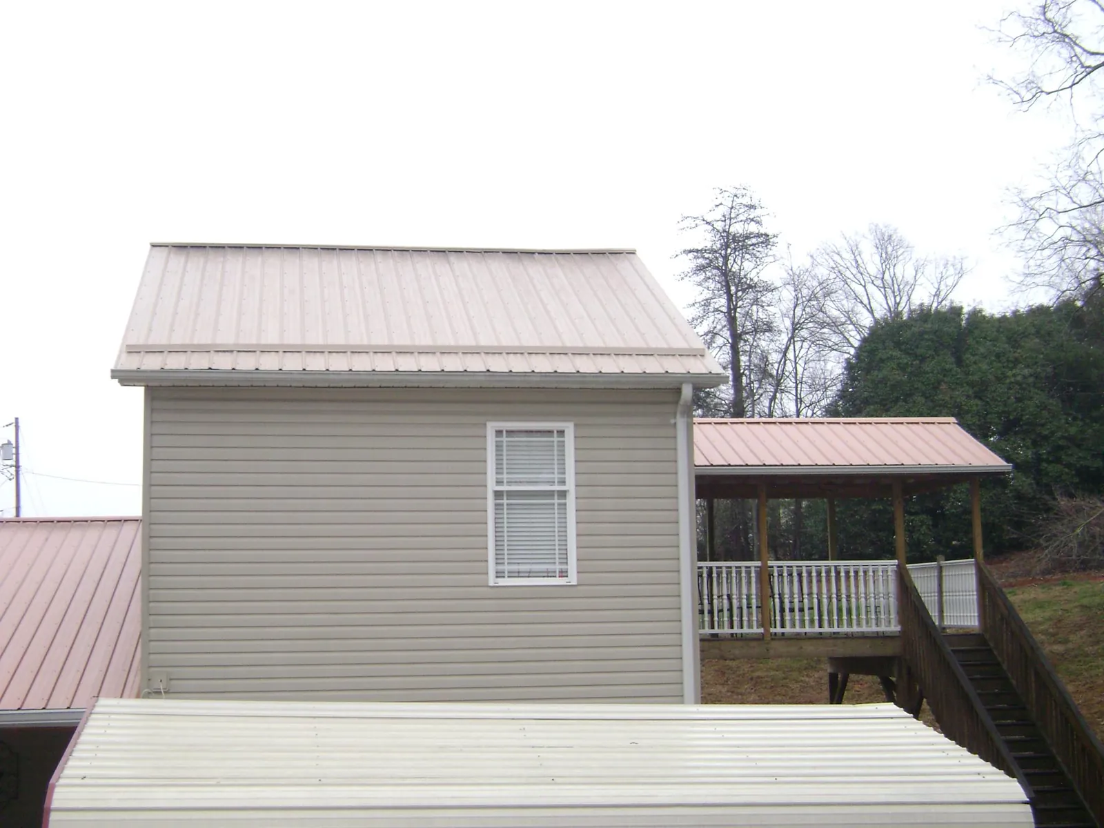 Tan metal roofs on a two story addition and attached porch, from a Roof Replacement job in Bonney Lake