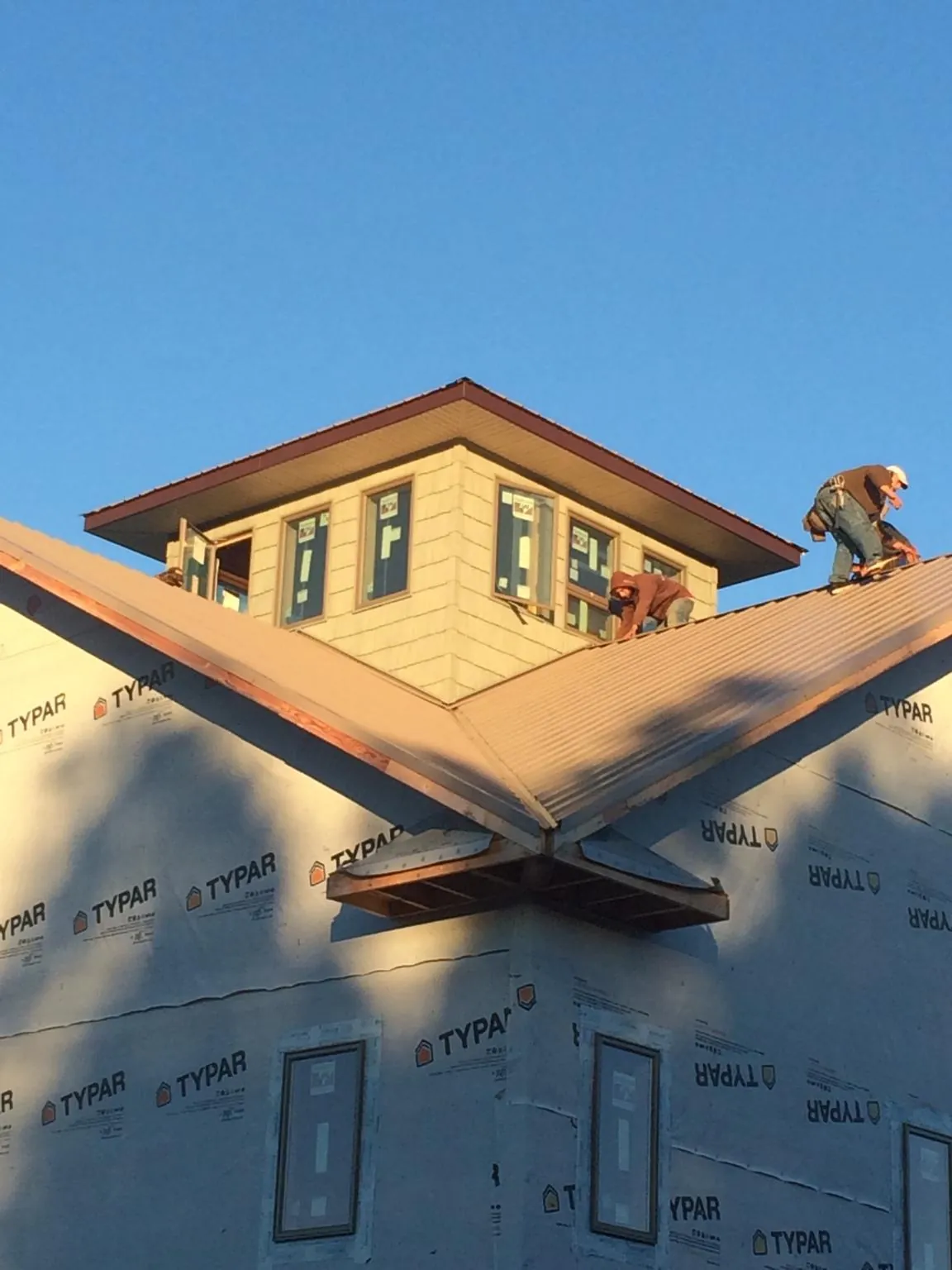 Roofers working around a rooftop cupola on a new metal roof at sunset — Roof Waterproofing in Bonney Lake by Roofing Brothers